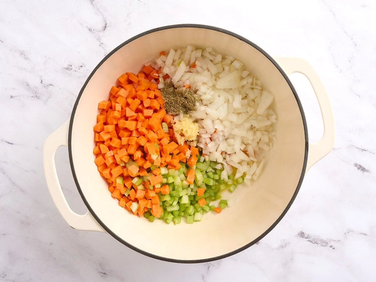 Diced carrots, onions, celery, minced garlic and seasonings in a pot.