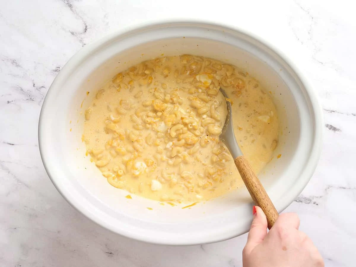 A spoon stirring midway through crockpot mac and cheese.