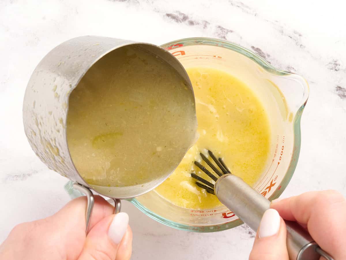 Broth being poured into eggs to temper them.