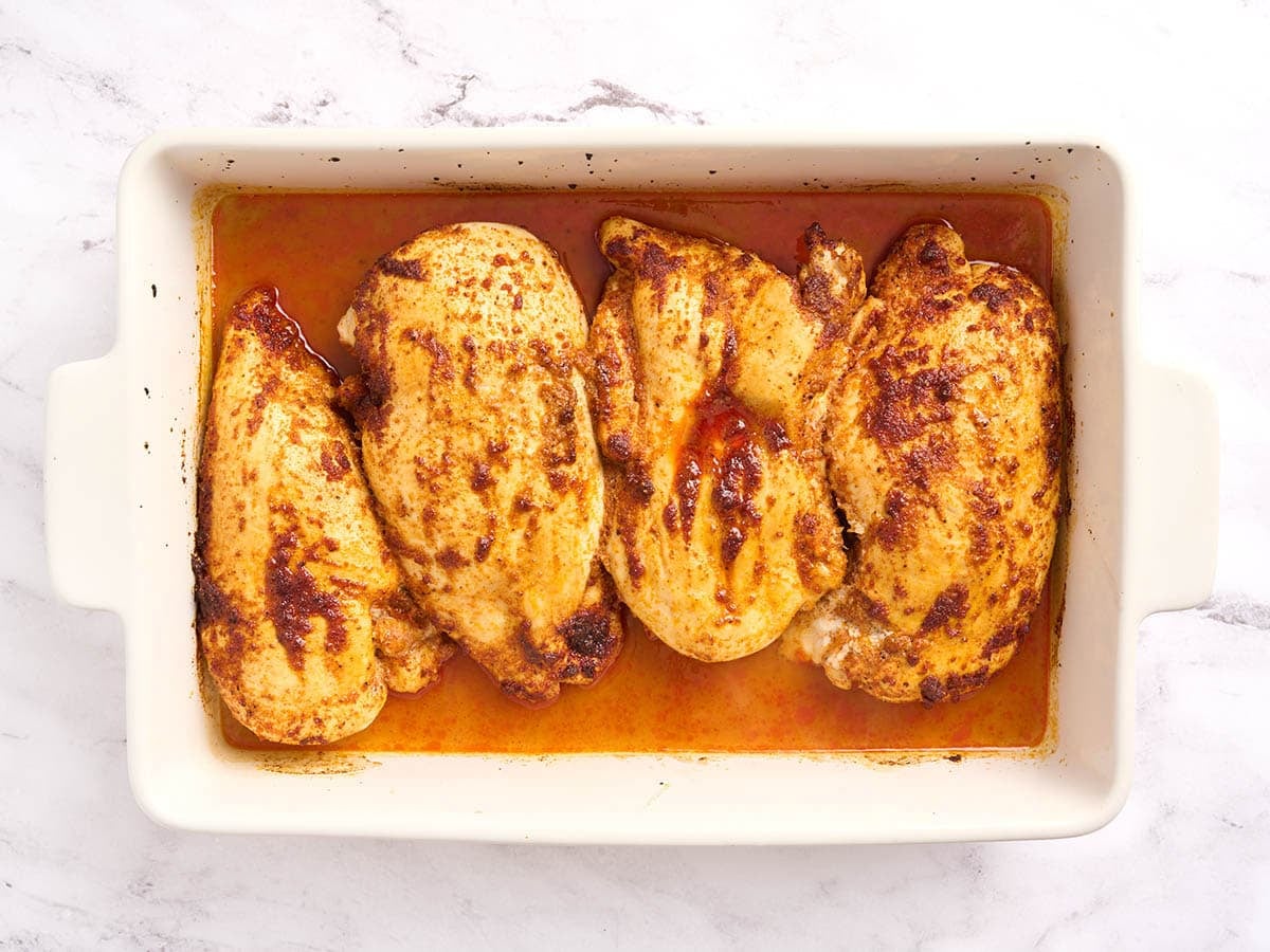 Overhead view of baked chicken breasts in a baking dish.