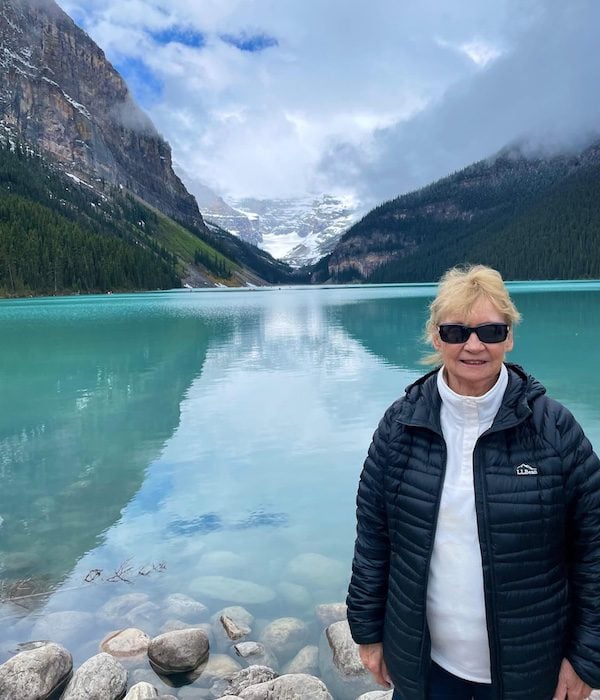 A woman poses in front of Lake Louise, Alberta. How to dress for safety while travelling