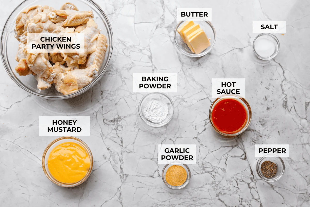 Get ready to get a little messy with these gold fever chicken wings! Baked until crispy and tossed in a sweet, tangy, buttery sauce with a kick of heat, they're perfect for game day, parties, or anytime a wing craving hits! Overhead shot of labeled ingredients.