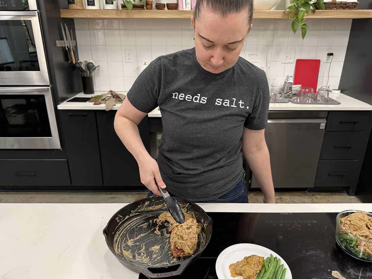 A women prepping smothered pork chops in a kitchen.