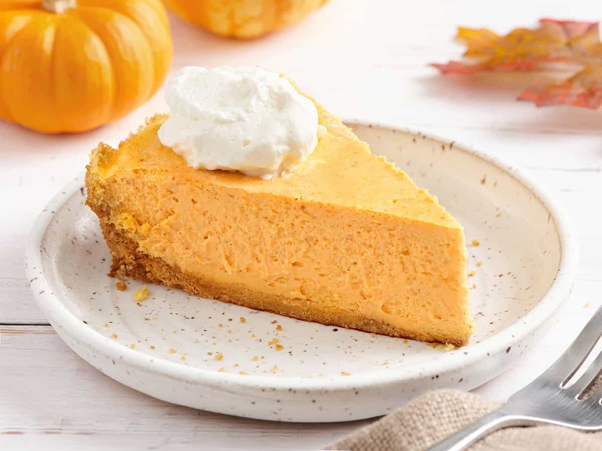 Sideview of a slice of pumpkin cheesecake on a plate.