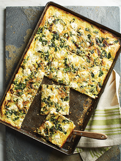 Sheet pan slab quiche with spinach, goat cheese, and caramelized onions.