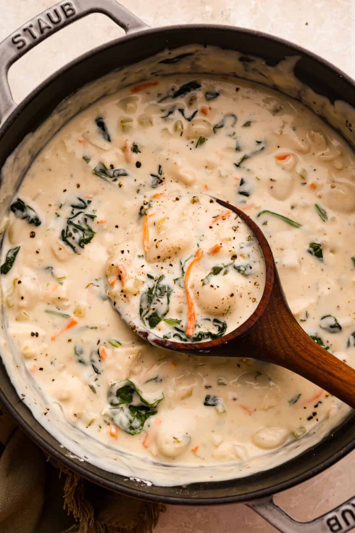 My creamy chicken gnocchi soup has everything I love about the Olive Garden favorite: tender chicken, pillowy gnocchi, fresh vegetables, and a rich, creamy broth. Even better, it comes together in just 30 minutes! Pot of creamy chicken gnocchi soup with a wooden spoon.