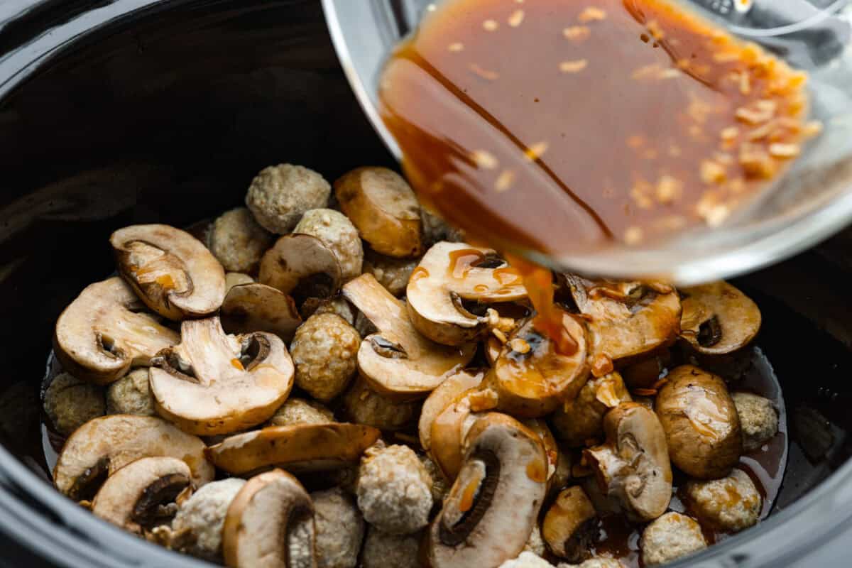 Sauce being poured over the mushrooms and meatballs. 